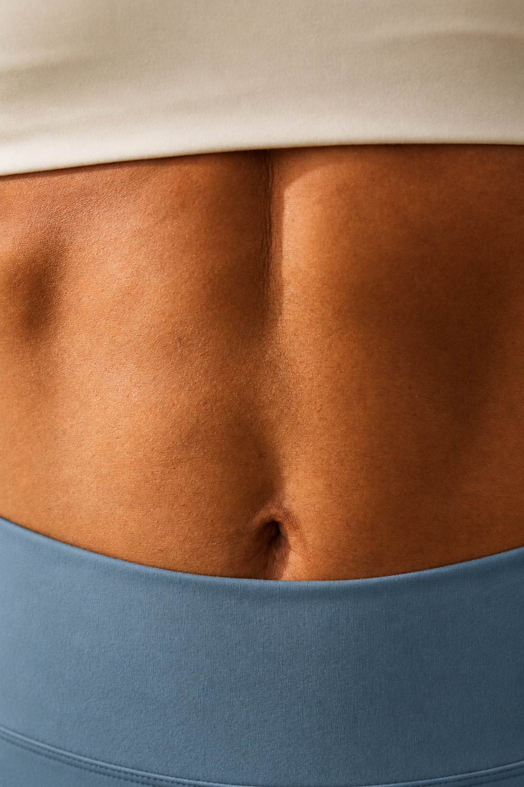 Close detail of a woman's midsection between a bone-coloured top and dusty blue leggings